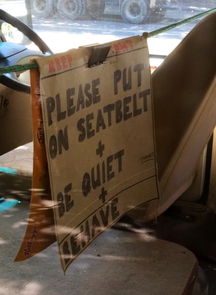 Sign in a school bus reads: 'Keep Out. Please put on seatbelt + be quiet + behave. Thanks'